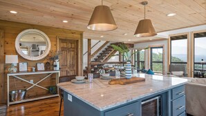 A kitchen with a central island, wooden ceiling, and large windows offering a view. - Spectacular View 3 Bd Luxury Smoky Mountain Cabin (Sevierville)