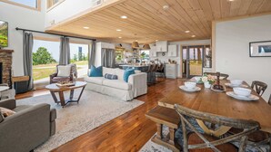 A spacious living area with a wooden ceiling, a dining table set for six, and a kitchen in the background. - Spectacular View 3 Bd Luxury Smoky Mountain Cabin (Sevierville)