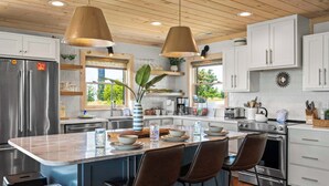 A modern kitchen with a central island, stainless steel appliances, and wooden ceiling. - Spectacular View 3 Bd Luxury Smoky Mountain Cabin (Sevierville)