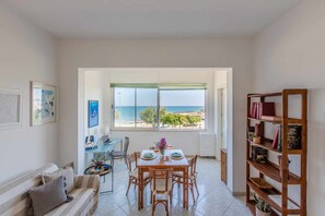 A room with a dining area, a sofa, a bookshelf, and a view of the sea. - Sea view terrace-Sea 50 mt away- Dishwasher- 2 bathrooms with shower- 5  guests. (Carovigno)
