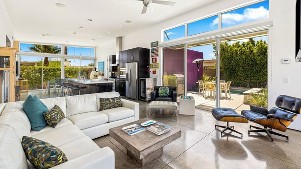 A spacious living room with a white sofa, a coffee table, and a dining area with chairs. - Troubadour - Mid Mod Getaway (Palm Springs)