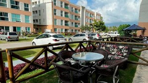 Un patio con mobiliario exterior, un edificio moderno al fondo y automóviles estacionados.