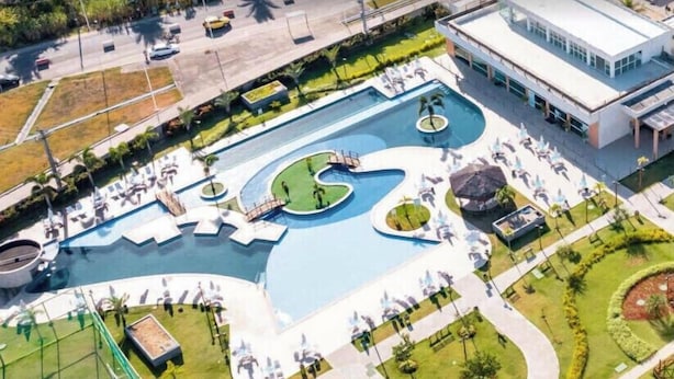 Vista aérea de un resort con una piscina grande, jardines ajardinados y un edificio moderno.