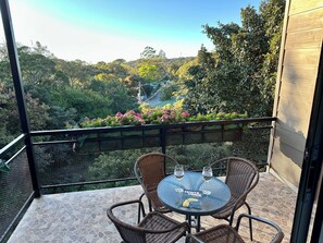 A balcony with wicker chairs, a glass table, and two wine glasses. - Wake Up with Birds in Monteverde - Forest Balcony & Walk to Reserves (Monteverde)