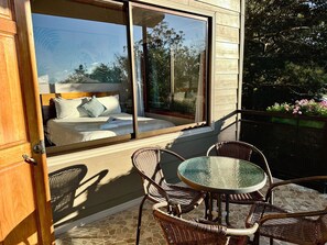 A bedroom with a large window, wicker furniture, and a stone-tiled patio. - Wake Up with Birds in Monteverde - Forest Balcony & Walk to Reserves (Monteverde)