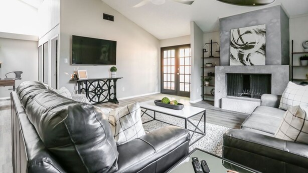 A modern living room with a black leather sofa, a coffee table, and a fireplace. - Industrial Chic South Lubbock 3/2 (Lubbock)
