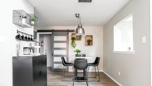 A modern kitchen with a dining area, featuring a black metal cabinet, a coffee machine, and a pendant light above the table. - Industrial Chic South Lubbock 3/2 (Lubbock)