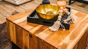 Een houten bijzettafeltje met een schaal, kaars en decoratieve objecten.