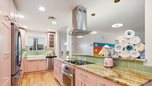 A kitchen with pink cabinets, a stainless steel refrigerator, a built-in oven, and a granite countertop.