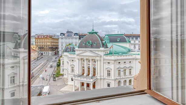 A view from a window overlooking a cityscape with historic buildings, including a prominent theater. - Hip Innere Stadt 3BR w/ Elevator, Best Location in Vienna, by Blueground (Vienna)