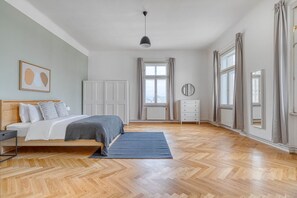 Quarto com cama, cômoda, espelho e janela com cortinas.