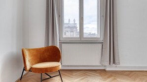 A room with a large window, a chair, and a radiator. - Hip Innere Stadt 3BR w/ Elevator, Best Location in Vienna, by Blueground (Vienna)