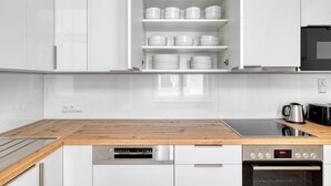 A modern kitchen with white cabinetry, a wooden countertop, a Bosch dishwasher, a Bosch oven, and a coffee maker. - Hip Innere Stadt 3BR w/ Elevator, Best Location in Vienna, by Blueground (Vienna)