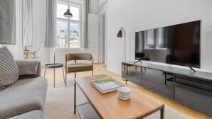 En moderne stue med en sofa, et træbord, et fjernsyn og en stol.