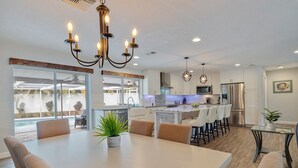 A modern kitchen with white cabinets, stainless steel appliances, and a central island with bar stools.