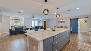 A spacious kitchen with a marble island, modern pendant lights, and a sliding barn door closet.