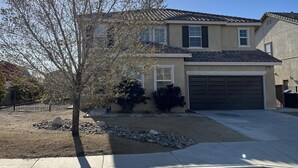A residential house with a garage, a small front yard with a tree, and a clear blue sky. - Lancaster Aerospace Basecamp (Lancaster)
