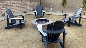 An outdoor seating area with Adirondack chairs and a fire pit. - Lancaster Aerospace Basecamp (Lancaster)