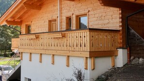 A wooden chalet with a balcony, a chimney, and a window overlooking a mountainous landscape. - Cosy apartment for 4 people with WIFI, TV and terrace (Wildschönau)