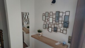 A hallway with a wooden bench, a wall-mounted mirror, and a potted plant.