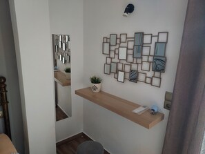 A hallway with a wooden bench, a wall-mounted mirror, and a potted plant.