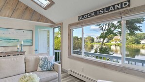 Una habitación con vistas a un lago, un cartel que dice 'BLOCK ISLAND' y un cuadro en la pared.