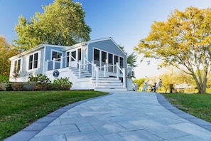 A single-story house with a porch, a pathway leading to the entrance, and bicycles parked outside.