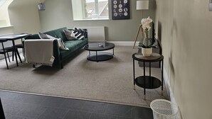 A cozy living room with a green sofa, a small coffee table, and a lamp.