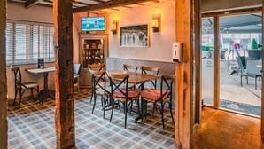 A cozy restaurant interior with wooden beams, checkered flooring, and a television on the wall.