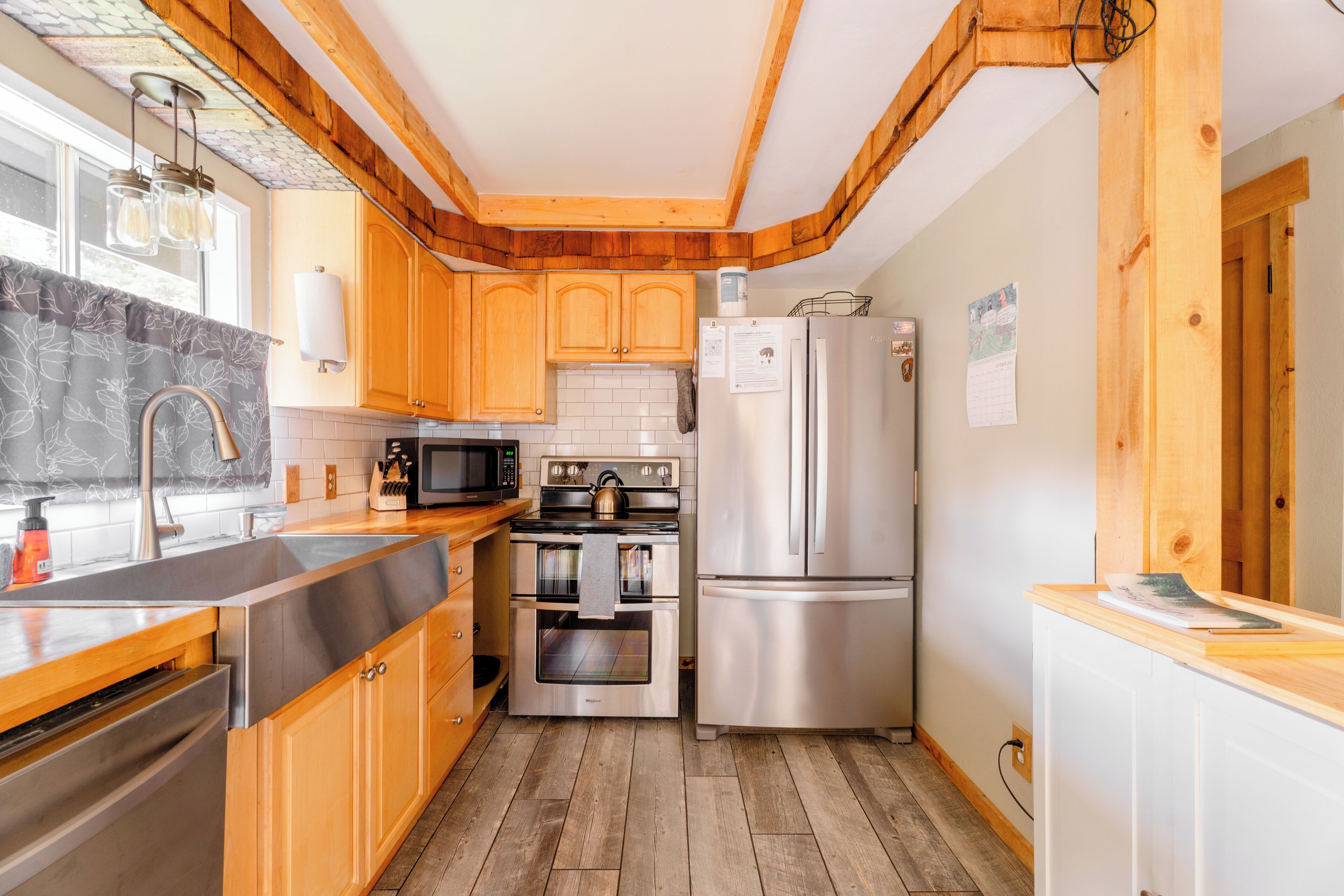 A kitchen with wooden cabinets, stainless steel appliances, a wooden countertop, and a tiled backsplash.