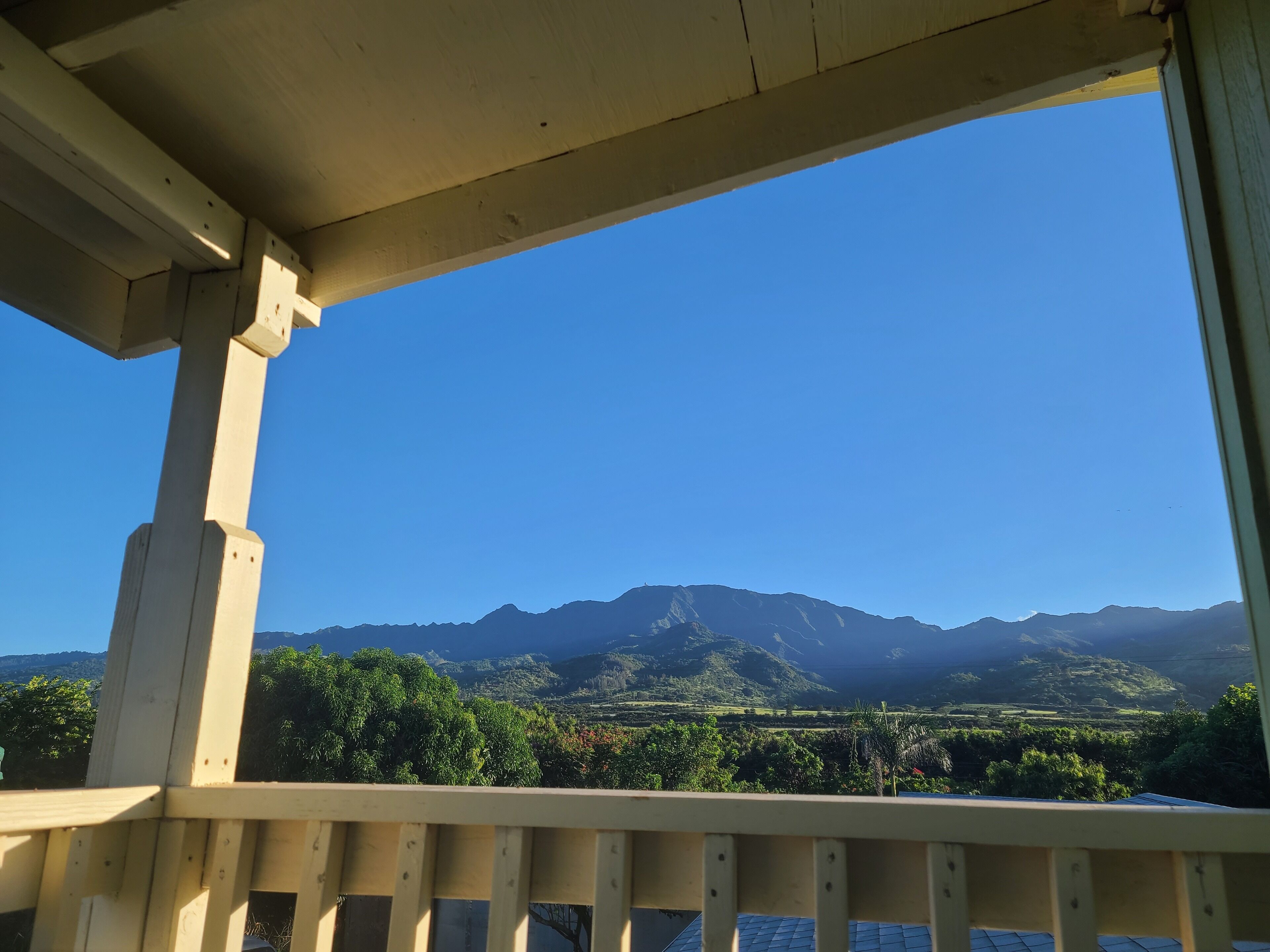 A wooden balcony with a view of mountains and greenery.