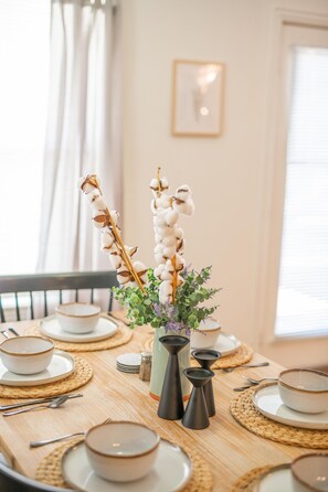 A dining table set with bowls, plates, and a vase with flowers. - PET/KID Friendly! Farmhouse Charmer! 20 mins to DT Austin! (Round Rock)