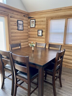 A wooden-paneled room with a round table and six chairs. - Cozy Lazy Dog Cabin (Red Lodge)