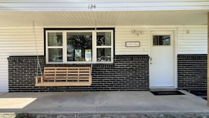 A building with a black brick exterior, a white door, and a bench outside.