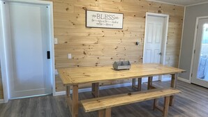 A wooden dining table with benches in a room with wooden panel walls and a door.
