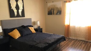 A bedroom with a large bed, a nightstand, a lamp, and a painting on the wall. - Charming  and cozy 2 bedroom apartment minutes from Ft. Jackson and VA Hospital (Columbia)