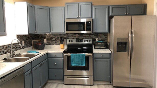 A modern kitchen with grey cabinets, stainless steel appliances, and a tiled backsplash. - Charming  and cozy 2 bedroom apartment minutes from Ft. Jackson and VA Hospital (Columbia)