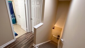 A hallway with a wooden floor, white doors, and a small shelf. - Charming  and cozy 2 bedroom apartment minutes from Ft. Jackson and VA Hospital (Columbia)