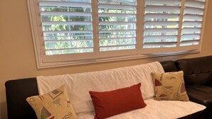 A dark brown leather sofa with a white textured cover, two patterned pillows, and a red accent pillow.