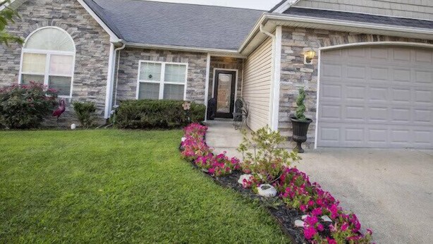 A two-story house with a stone facade, a front door, and a garage. - Comfy home in military community (Radcliff)