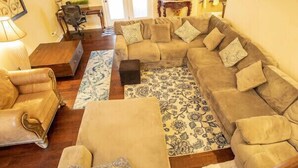 A living room with a beige sectional sofa, a small round table, and a patterned rug. - Comfy home in military community (Radcliff)
