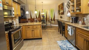 A kitchen with wooden cabinets, a granite countertop, a dining area with chairs, and pendant lighting. - Comfy home in military community (Radcliff)