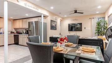 Una cocina moderna con comedor, televisión de pantalla plana y ventilador de techo.