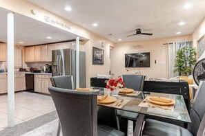 A modern kitchen with a dining area, a flat-screen TV, and a ceiling fan. - Sweet Home Georgia Amour (Peachtree Corners)
