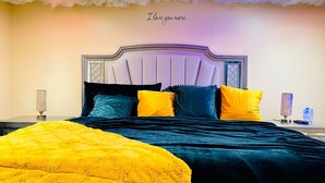 A bedroom with a bed, pillows, a nightstand, and a wall with a cloud design and text. - Sweet Home Georgia Amour (Peachtree Corners)