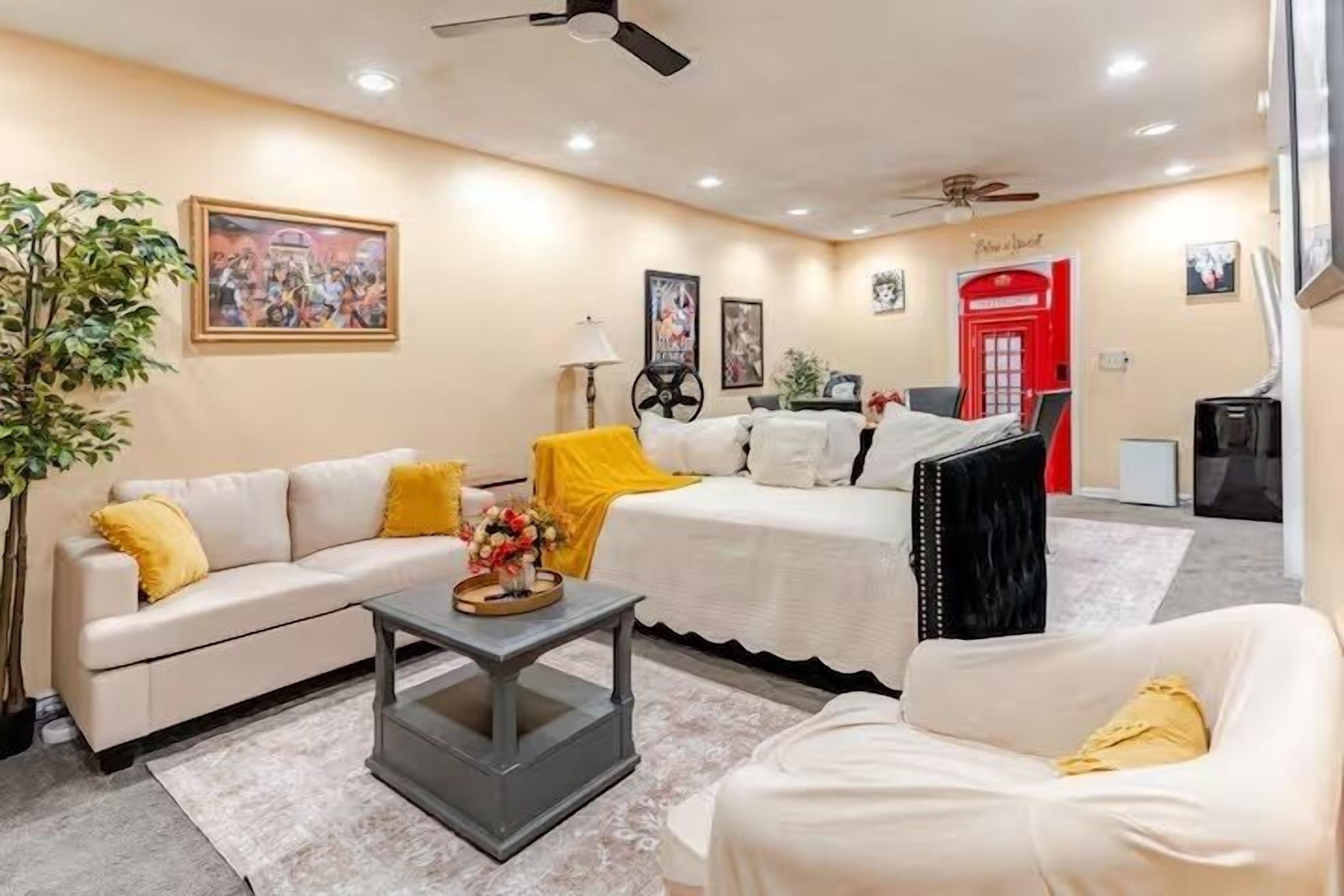A hotel room with a sofa, a bed, a coffee table, and a red door.