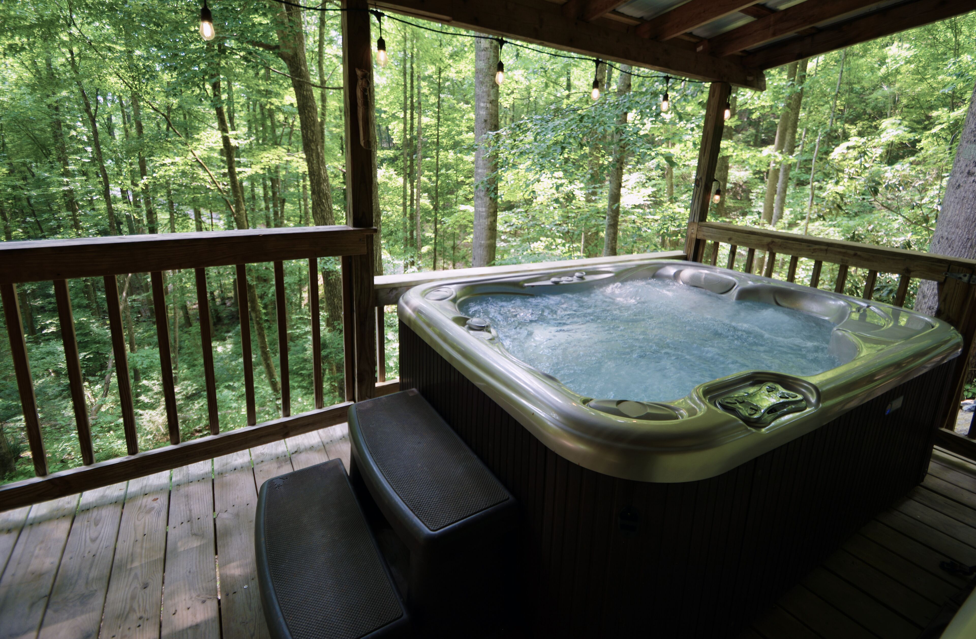 Un jacuzzi en una terraza de madera con vistas a un bosque.