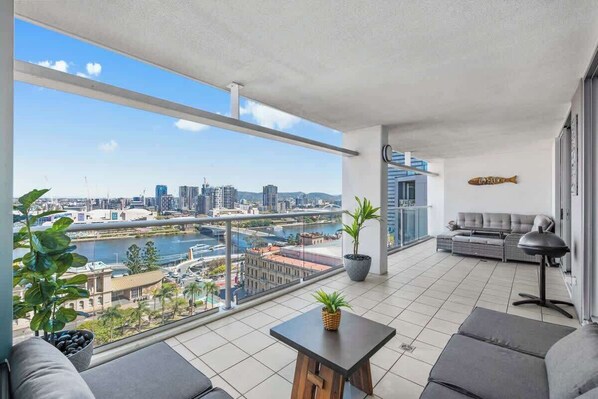 A balcony with a city view, a sofa, a table, and a lamp.