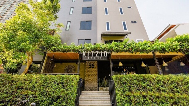 A modern hotel with a sign reading "KITZIO HOTEL" and a staircase leading to the entrance. - Kitzio House Hotel (Bangkok)