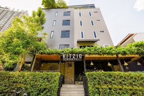 A modern hotel with a sign reading "KITZIO HOTEL" and a staircase leading to the entrance. - Kitzio House Hotel (Bangkok)
